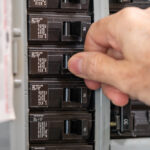 mans hand flipping a breaker switch